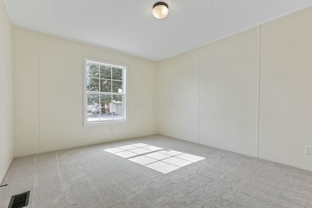 carpeted empty room with visible vents and a textured ceiling