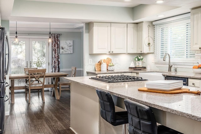 kitchen featuring light stone counters, dark hardwood / wood-style flooring, ornamental molding, and a raised ceiling