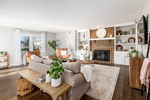 living room with built in features, dark hardwood / wood-style floors, and a brick fireplace