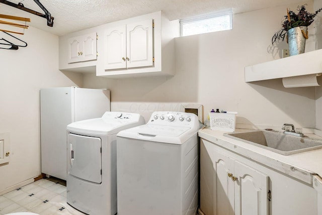 laundry area featuring cabinets, separate washer and dryer, sink, and a textured ceiling