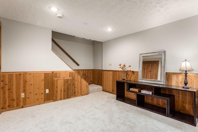 interior space featuring wooden walls, carpet floors, and a textured ceiling