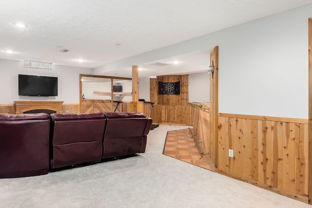 living room with a textured ceiling, light carpet, and wood walls