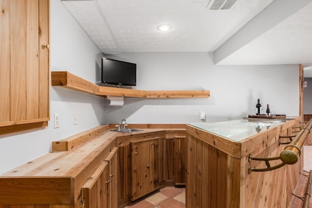 kitchen featuring sink, light tile patterned floors, a textured ceiling, and kitchen peninsula