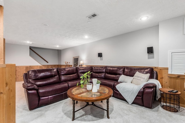 carpeted living room featuring wooden walls and a textured ceiling