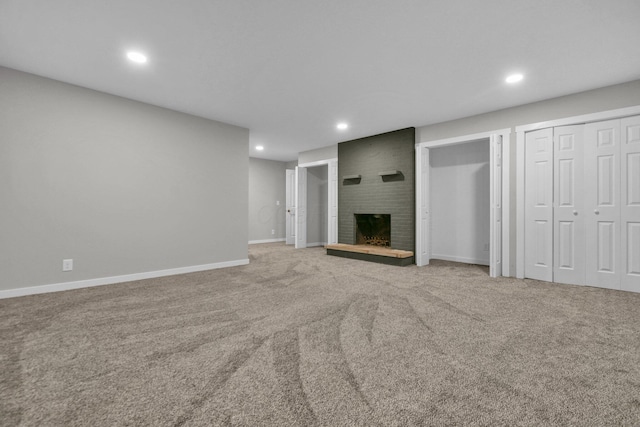 unfurnished living room featuring a brick fireplace and carpet floors