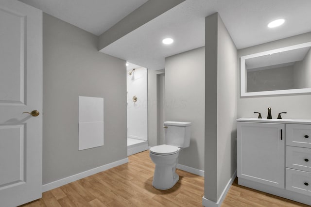 bathroom with hardwood / wood-style flooring, vanity, toilet, and a shower