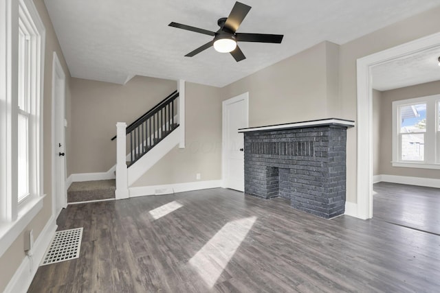 unfurnished living room featuring ceiling fan, dark hardwood / wood-style floors, and a fireplace