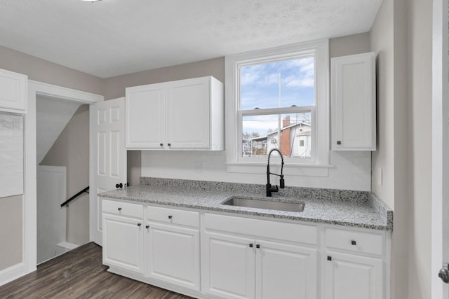 kitchen with white cabinetry, light stone countertops, sink, and dark hardwood / wood-style flooring