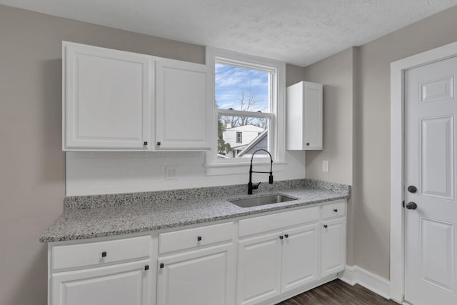 kitchen featuring dark hardwood / wood-style flooring, sink, white cabinets, and light stone counters