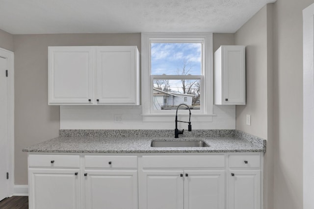 kitchen featuring white cabinetry, tasteful backsplash, sink, and light stone counters