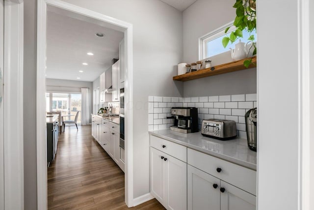 kitchen with tasteful backsplash, white cabinetry, dark wood-type flooring, and light stone counters