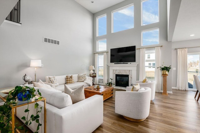 living room with a high end fireplace and wood-type flooring