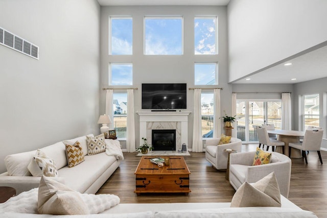 living room featuring a high ceiling, dark hardwood / wood-style floors, a wealth of natural light, and a fireplace