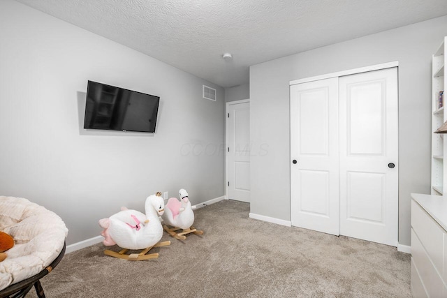 game room with light colored carpet and a textured ceiling