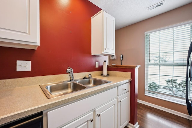 kitchen featuring sink, hardwood / wood-style flooring, a textured ceiling, and white cabinets