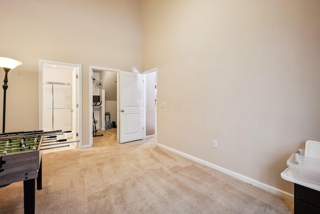 recreation room with light carpet and a high ceiling