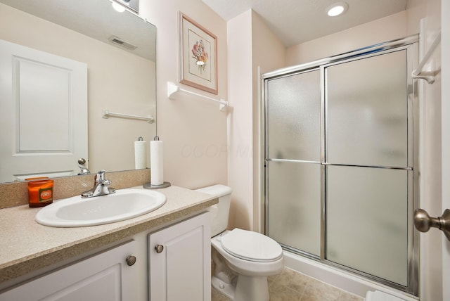 bathroom featuring tile patterned floors, vanity, toilet, and a shower with shower door