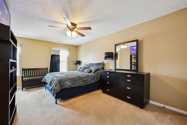 bedroom with ceiling fan, light carpet, and a textured ceiling