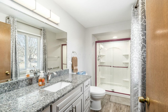 bathroom featuring wood-type flooring, toilet, vanity, and walk in shower