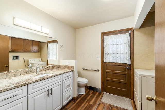 bathroom with wood-type flooring, washer / dryer, vanity, and toilet