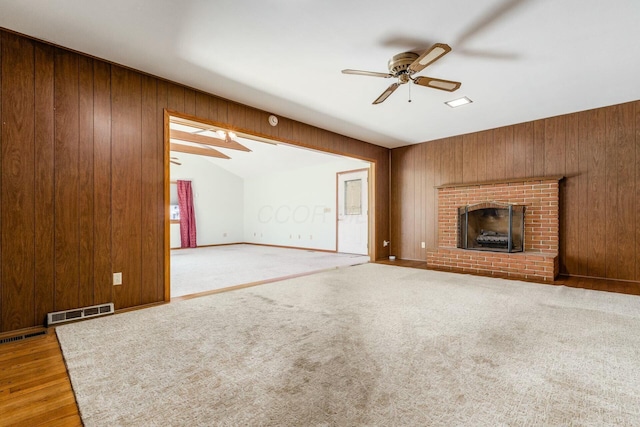 unfurnished living room featuring ceiling fan, a fireplace, wood walls, and vaulted ceiling with beams