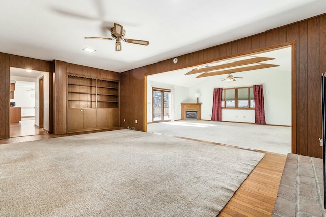 unfurnished living room with vaulted ceiling, built in features, and ceiling fan