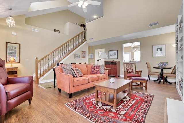 living room featuring hardwood / wood-style flooring, high vaulted ceiling, and ceiling fan with notable chandelier