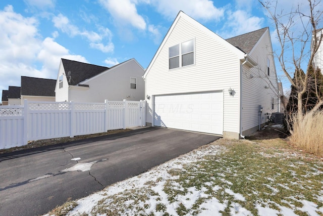 view of snow covered exterior featuring central AC and a garage