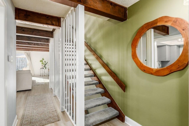 staircase featuring hardwood / wood-style floors and beamed ceiling