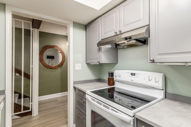 kitchen with electric stove, white cabinetry, and light hardwood / wood-style floors