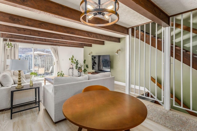 living room featuring an inviting chandelier, beam ceiling, a textured ceiling, and light wood-type flooring