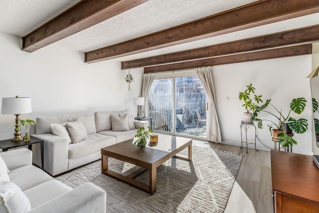 living room featuring beamed ceiling, a textured ceiling, and light wood-type flooring