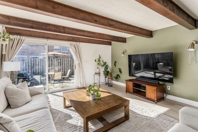 living room featuring beam ceiling, light hardwood / wood-style floors, and a textured ceiling