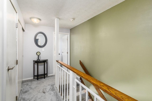 hall with light carpet and a textured ceiling