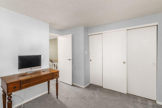 carpeted office space featuring a textured ceiling