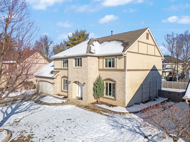 snow covered rear of property featuring a garage