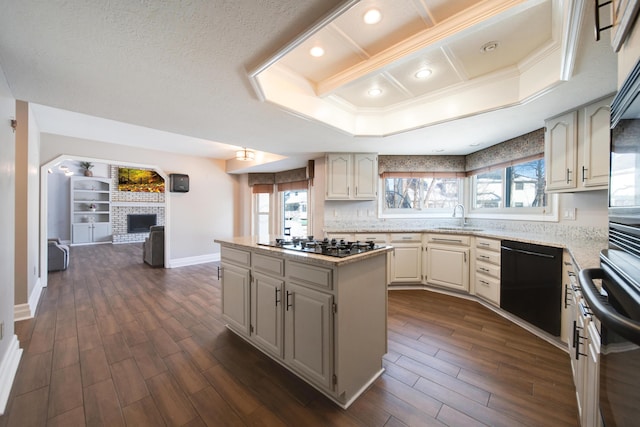 kitchen featuring a brick fireplace, light stone countertops, stainless steel gas cooktop, and a kitchen island