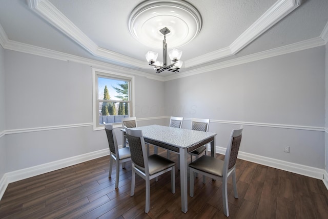 dining area with a raised ceiling, crown molding, dark wood-type flooring, and a chandelier