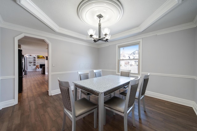 dining area with a raised ceiling, ornamental molding, dark hardwood / wood-style floors, and an inviting chandelier