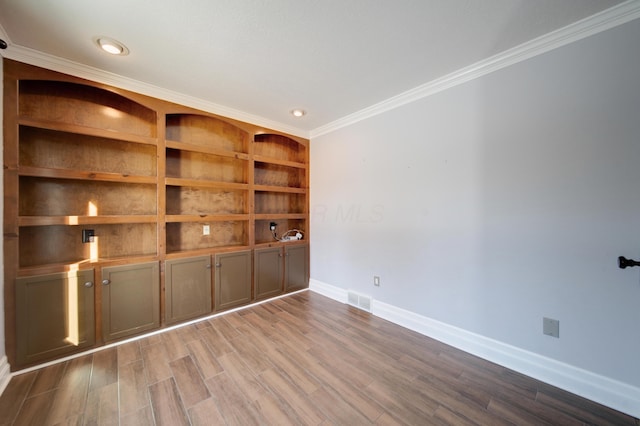 unfurnished room featuring hardwood / wood-style flooring, ornamental molding, and built in shelves