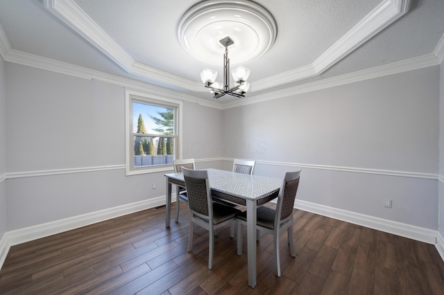 dining area featuring a notable chandelier, a tray ceiling, ornamental molding, and dark hardwood / wood-style floors