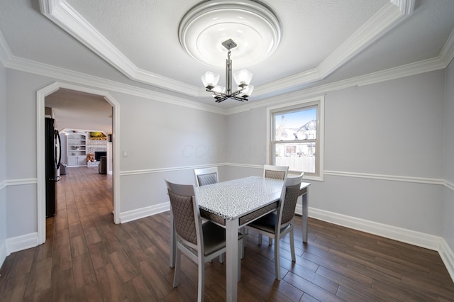 dining room featuring a tray ceiling, dark wood-type flooring, ornamental molding, and a chandelier