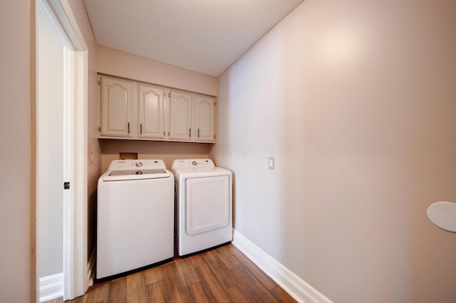 clothes washing area featuring independent washer and dryer, dark hardwood / wood-style floors, and cabinets