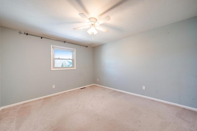 carpeted spare room with a textured ceiling and ceiling fan