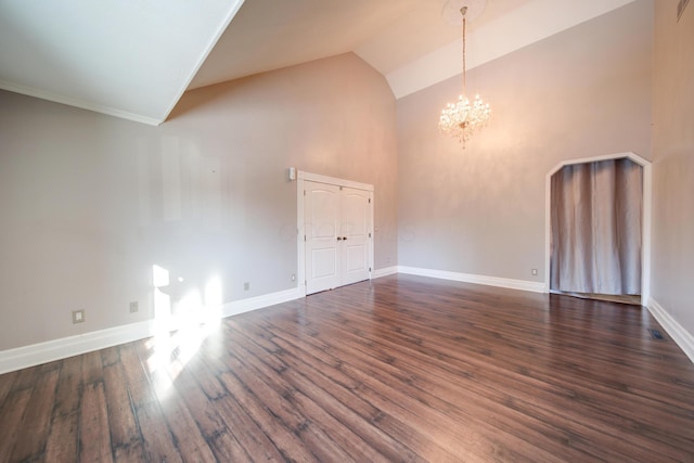 empty room with dark hardwood / wood-style floors, a chandelier, and high vaulted ceiling