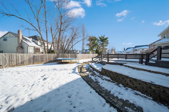 yard layered in snow featuring a trampoline