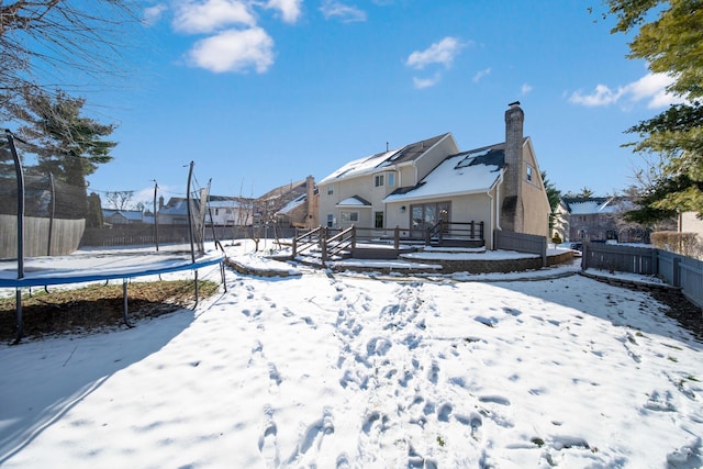 snow covered back of property featuring a trampoline