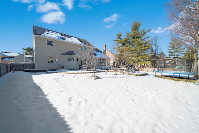 snow covered rear of property with a trampoline