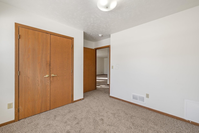 unfurnished bedroom featuring light carpet, a closet, and a textured ceiling