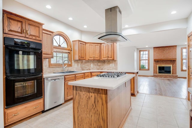 kitchen with sink, island range hood, a kitchen island, a wealth of natural light, and stainless steel appliances